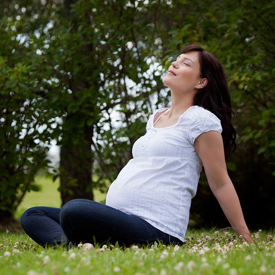 A pregnant woman sitting on grass