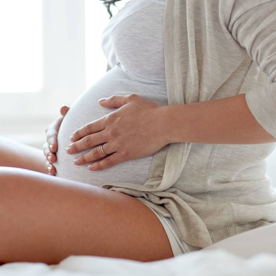 Pregnant woman sitting on a bed